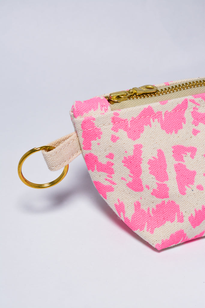 Small pouch with pink abstract pattern and gold zipper on a light gray background